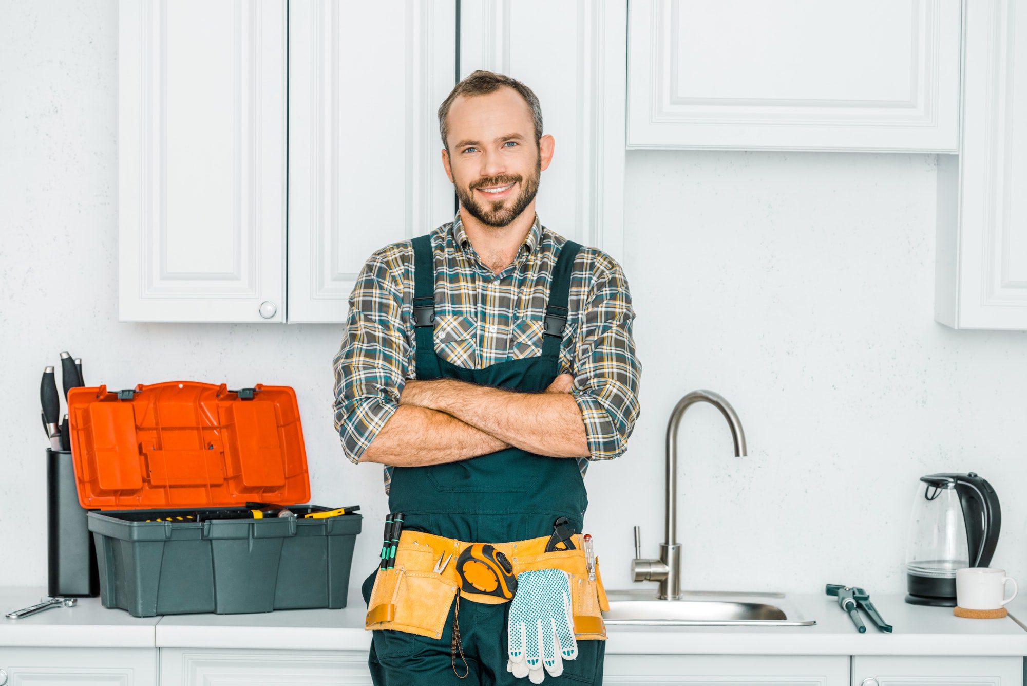 smiling-handsome-plumber-standing-with-crossed-arms-and-looking-at-camera-in-kitchen.jpg